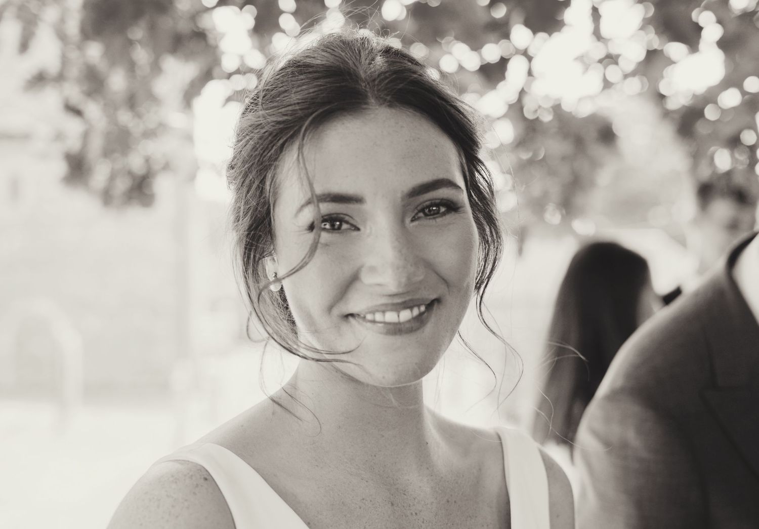 Elegant bride smiling softly in black and white portrait photo with bokeh background.