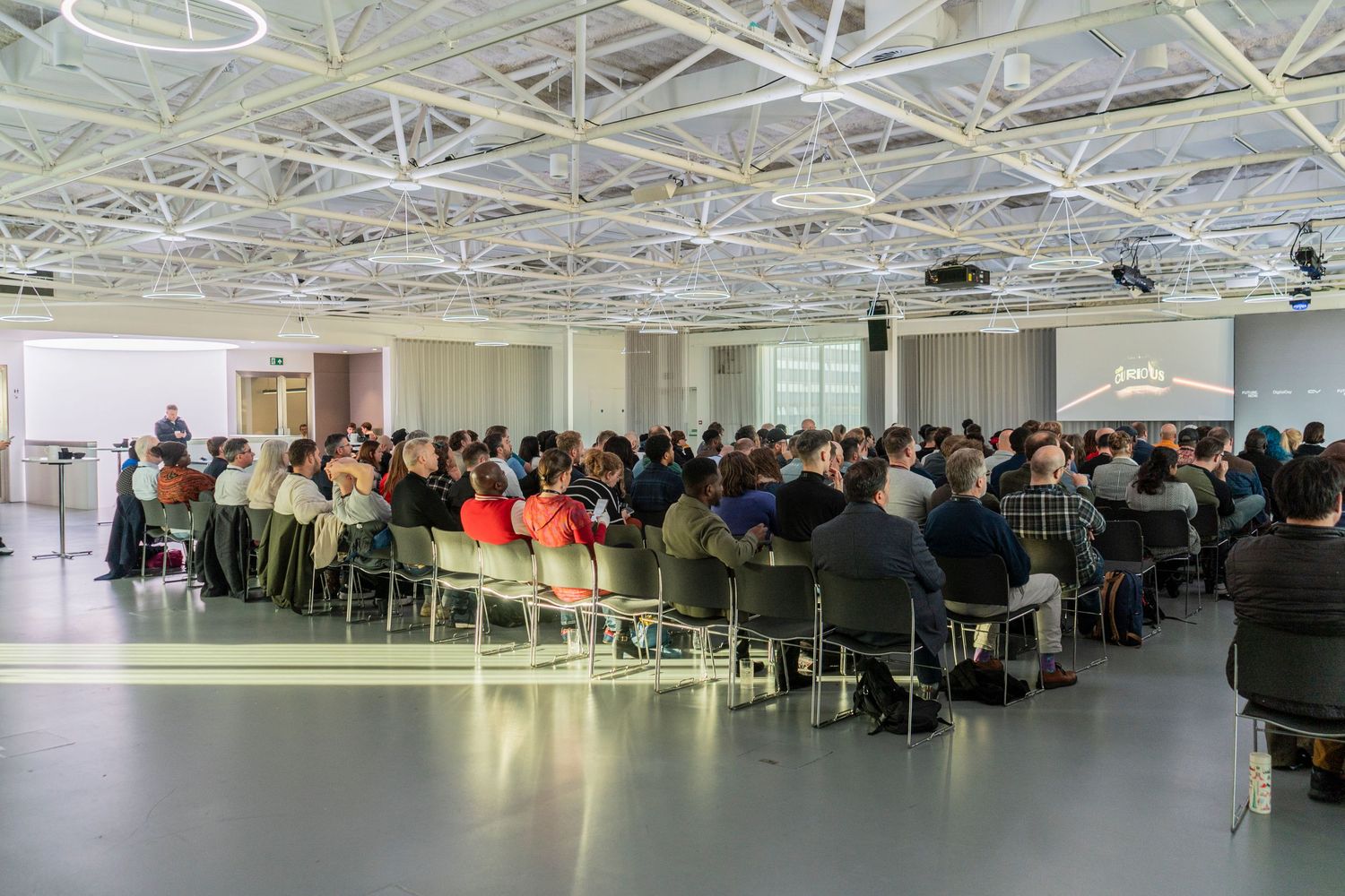 Large audience seated in a modern conference hall during a presentation.
