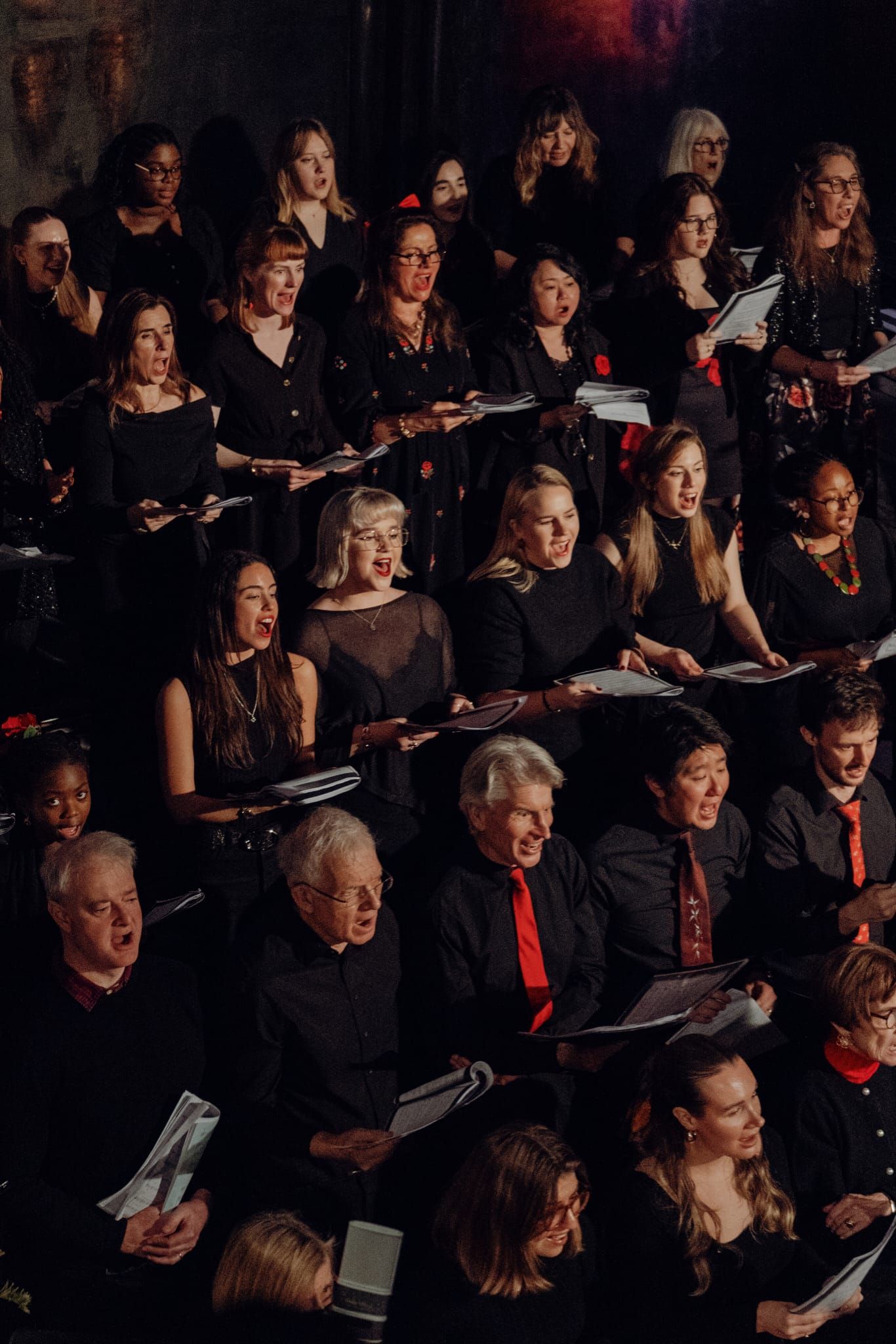 Large choir dressed in black performing at a formal choral concert event.
