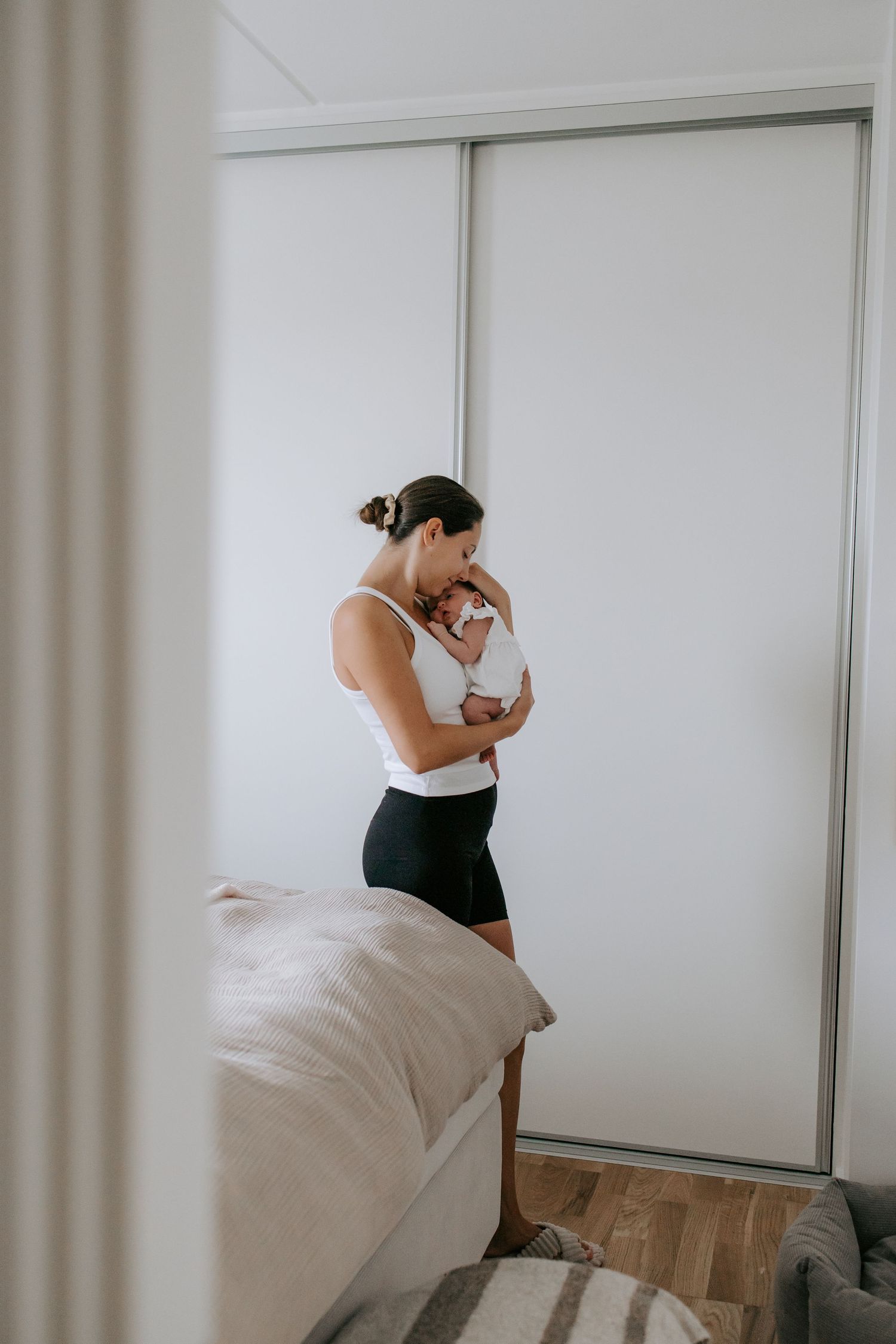 New mother standing in bedroom cradling and bonding with her newborn baby.