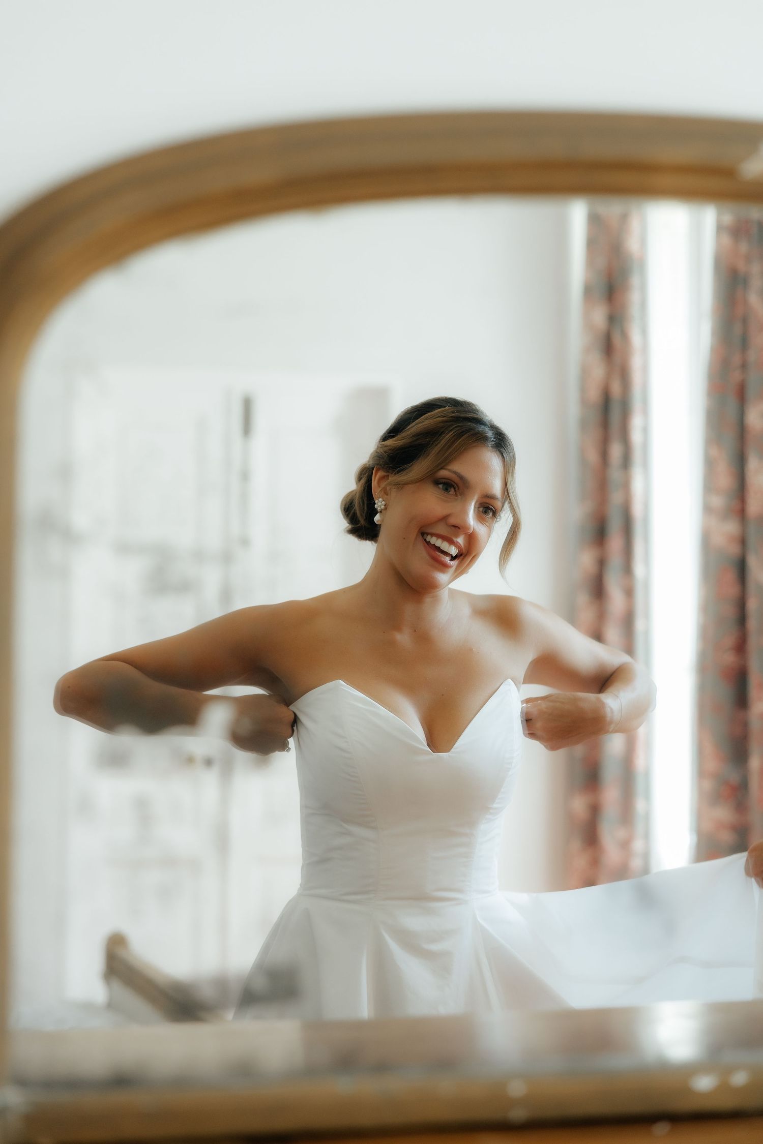 White wedding dress detail through a mirror reflection in an elegant room.