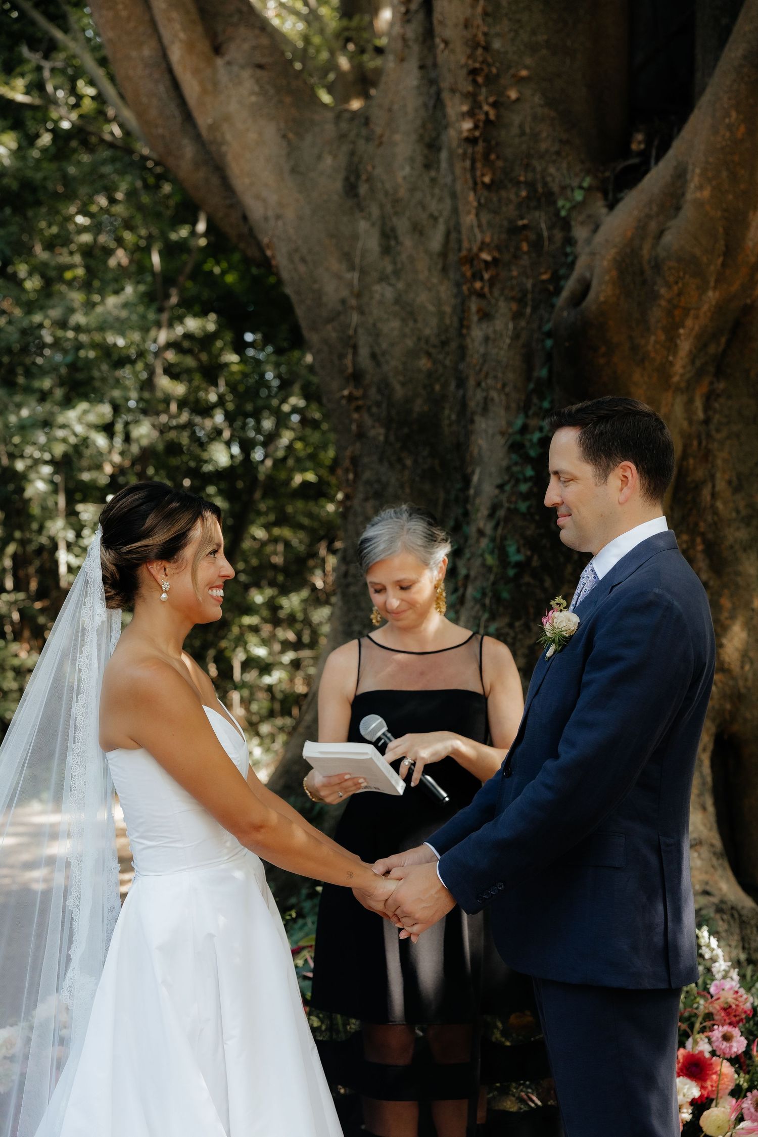 Wedding ceremony sequence showing ring exchange under a large tree outdoors.