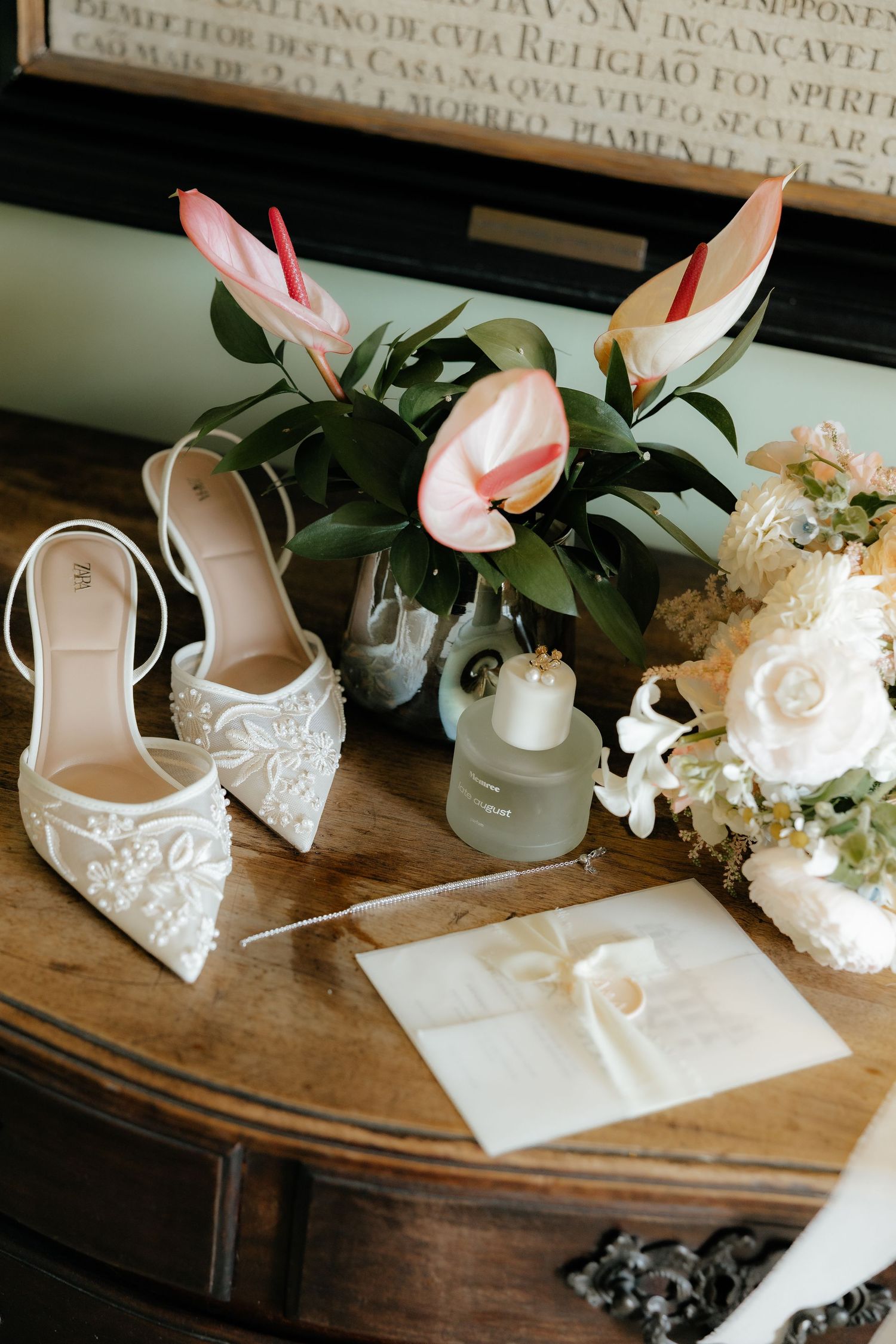 White lace wedding shoes and elegant stationery displayed on a rustic wooden table with delicate floral arrangements.