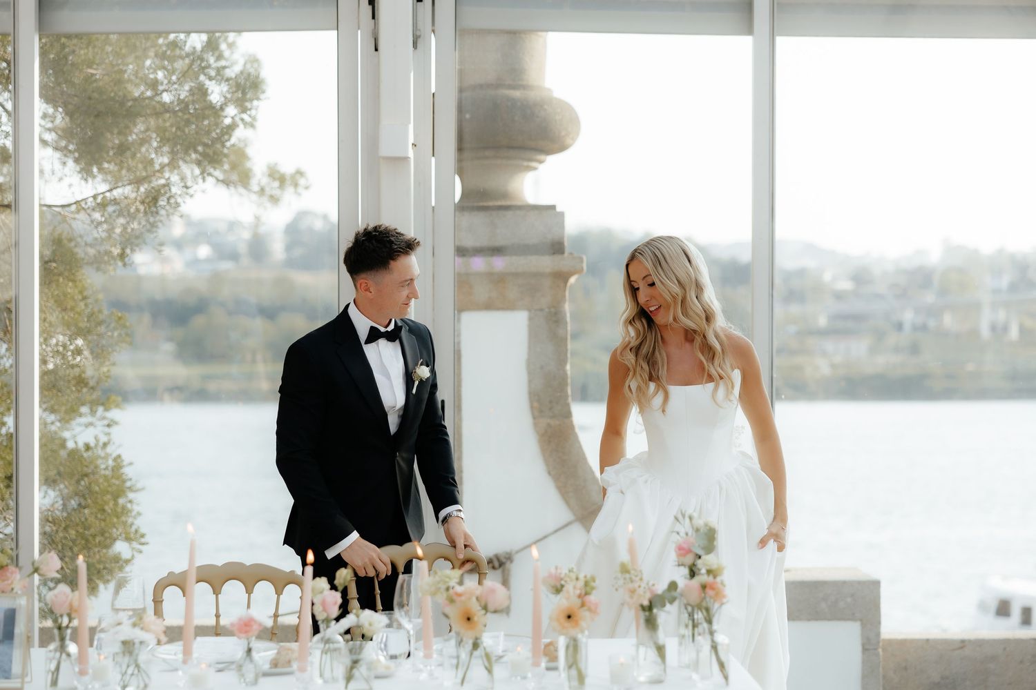 Elegant wedding couple shares a romantic moment by the waterfront in formal attire during their celebration.