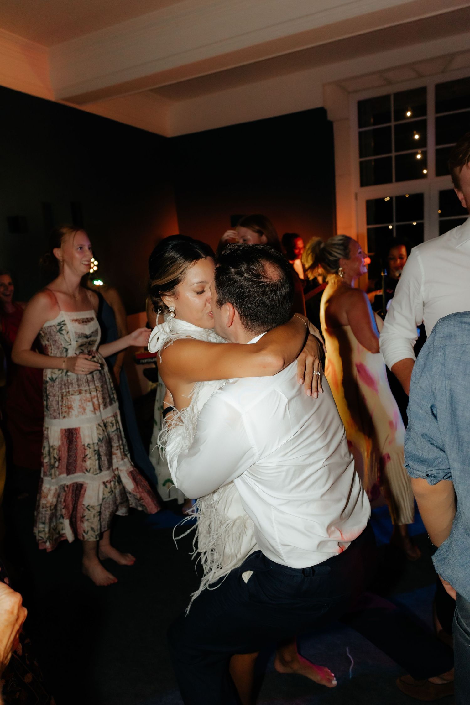 People dancing and celebrating at a dimly lit party venue with festive atmosphere.