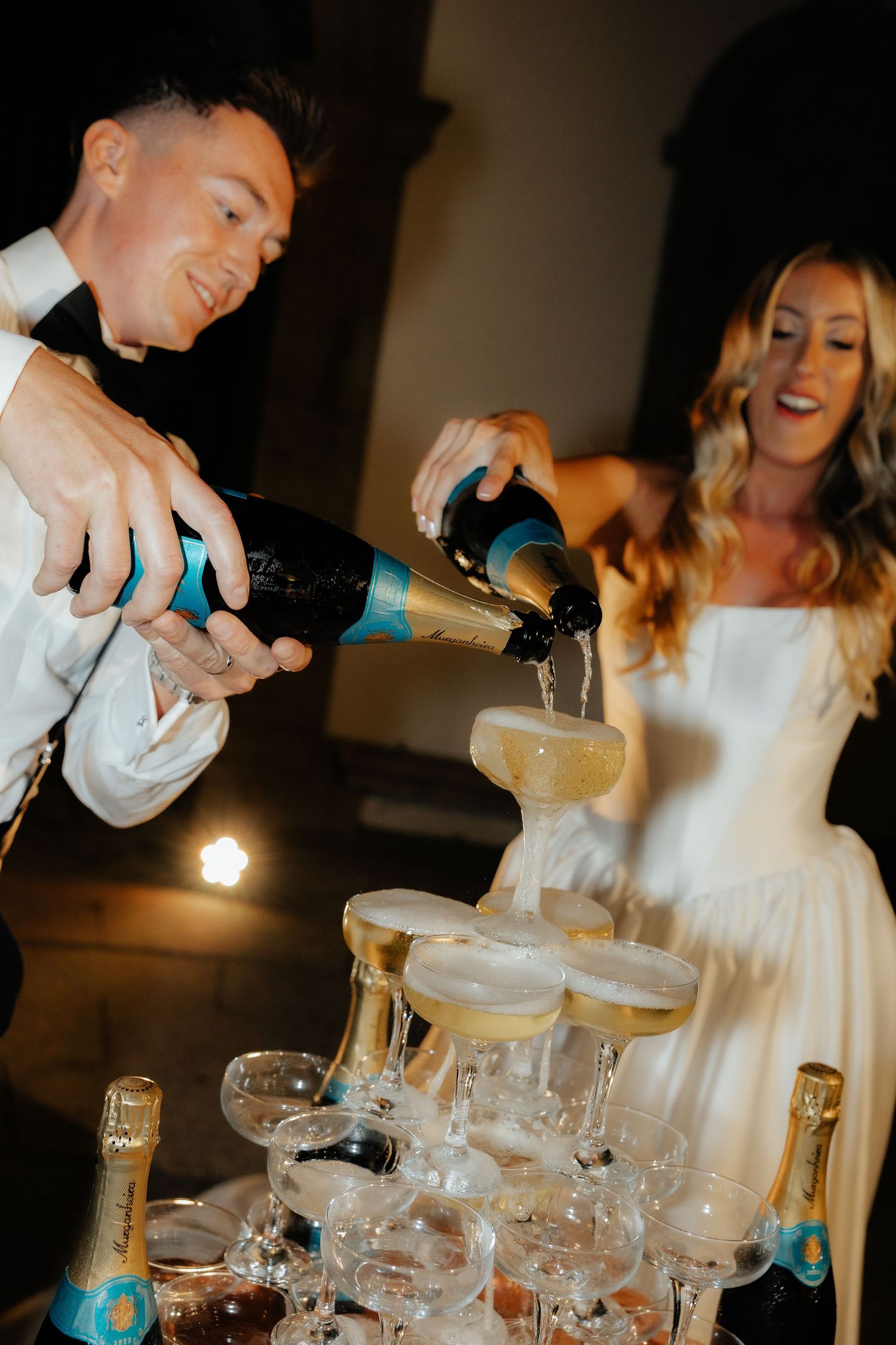 Champagne being poured into stacked glasses creating a cascading effect at a celebration.