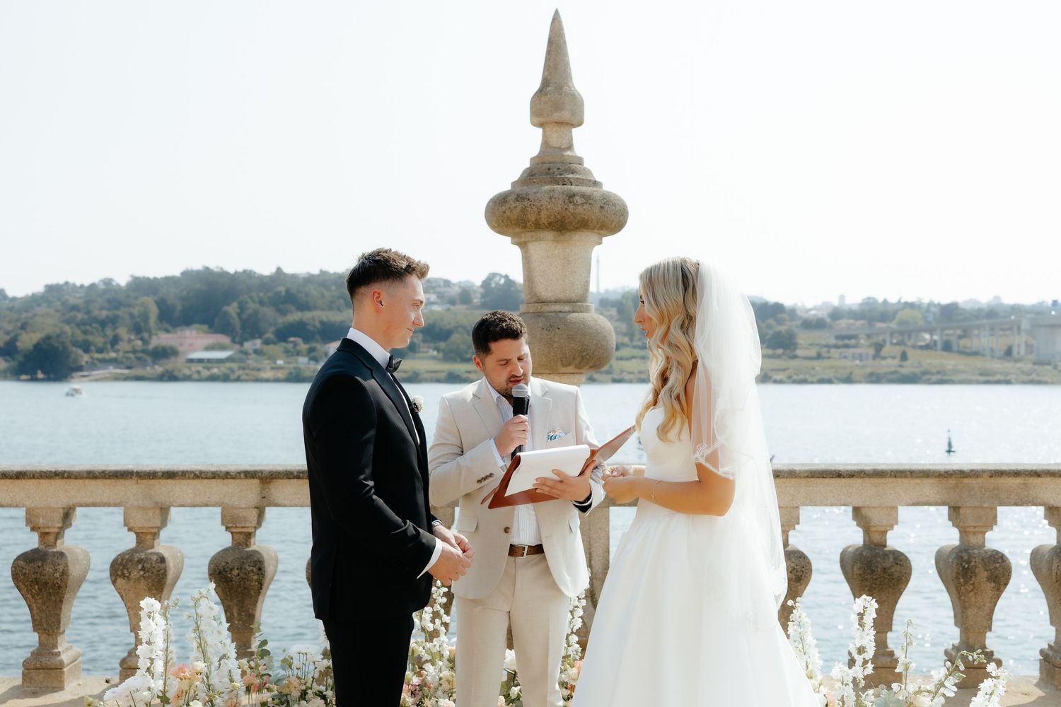 Elegant wedding couple sharing intimate moments on a stone balcony overlooking a scenic coastal view.