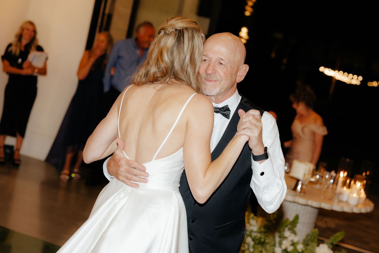 Bride and groom share an intimate first dance, with the groom smiling warmly while holding his bride close.