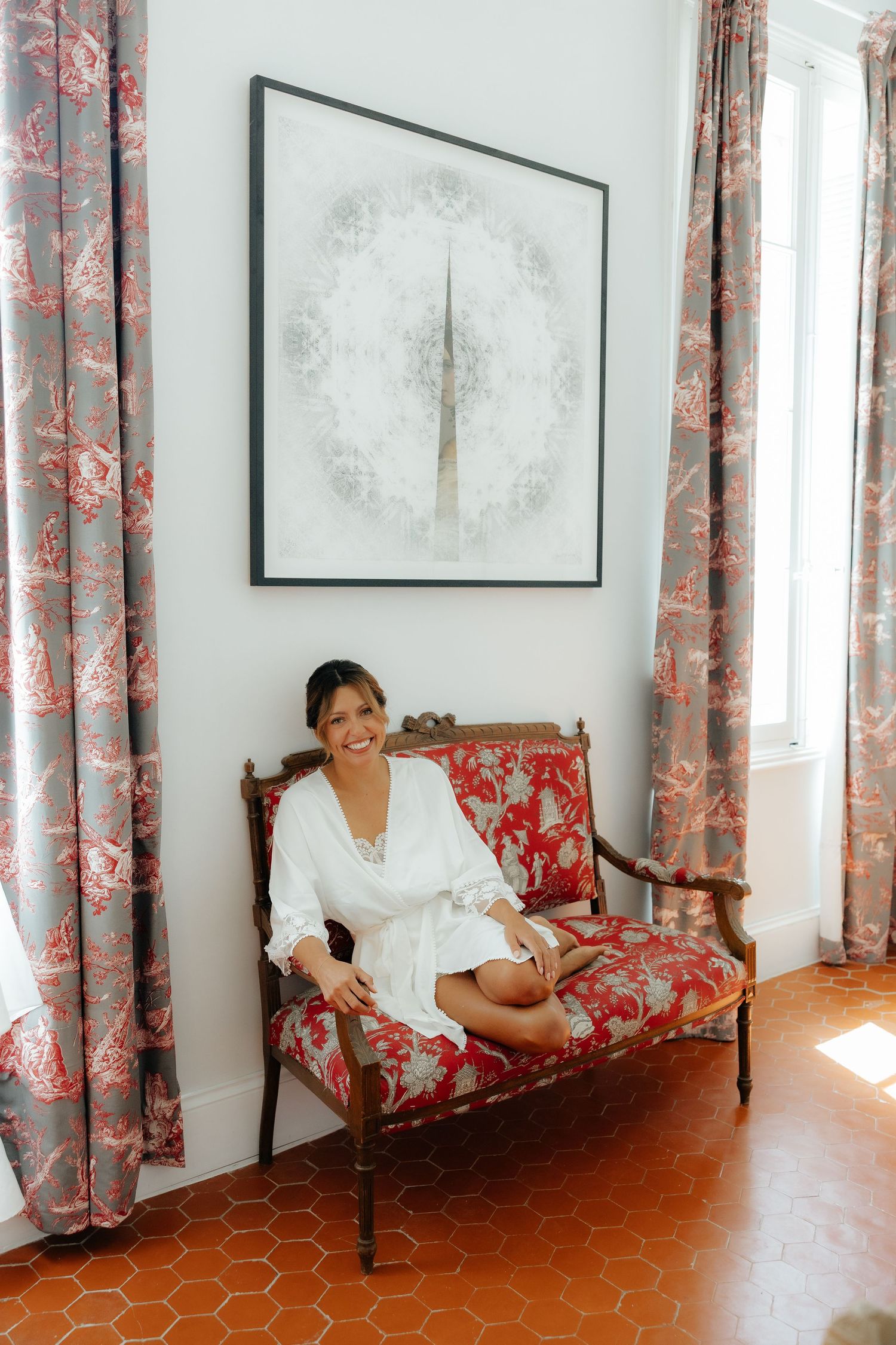 Wedding preparation scene with floral curtains and red tile floor in bright sunlit room.