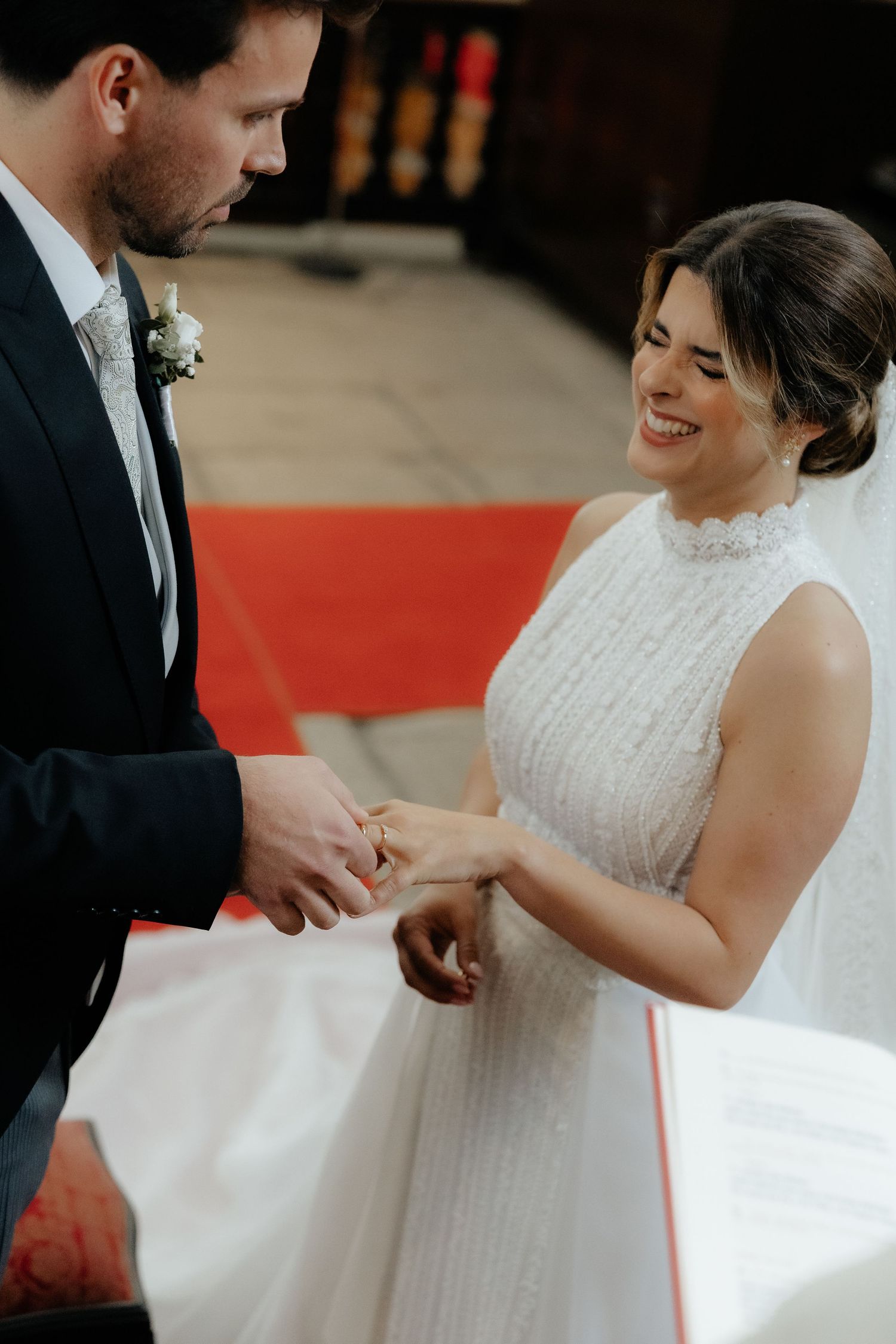 Smiling bride receives wedding ring from groom during romantic church ceremony exchange of vows.