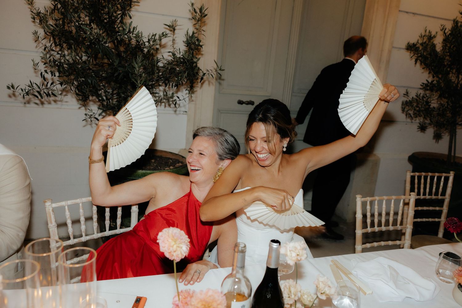 Wedding reception celebration with guests holding paper fans and enjoying festivities at a decorated outdoor venue.