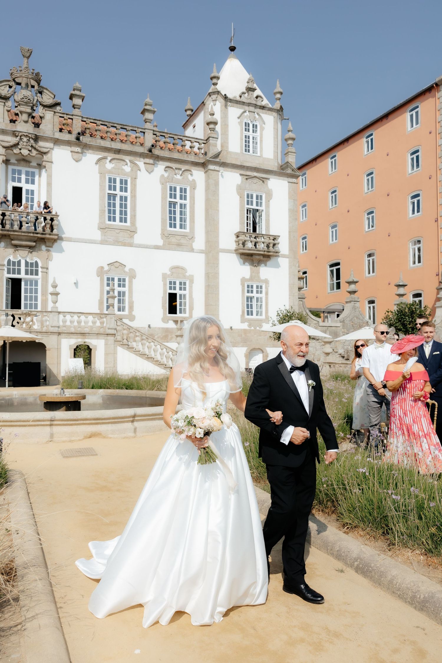 A sequence of outdoor wedding photos taken in front of a grand historic palace with peach-colored walls and ornate details.