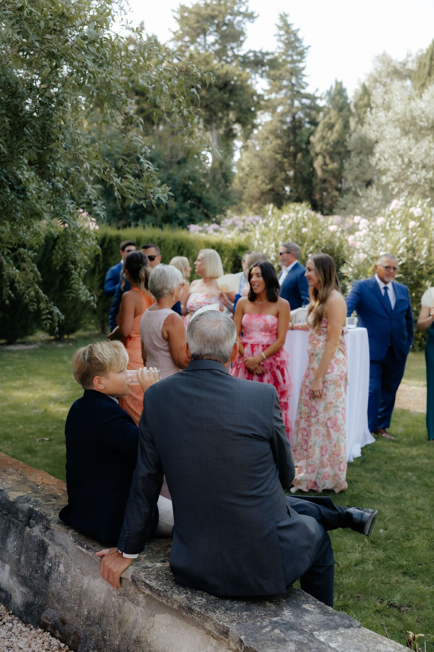 Wedding guests seated on fallen tree trunk during outdoor ceremony.