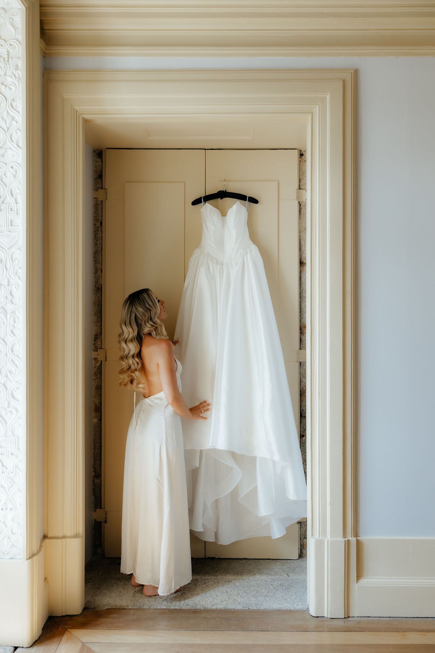 A series of white wedding dresses hanging in elegant cream-colored doorways creates a dreamy bridal display.
