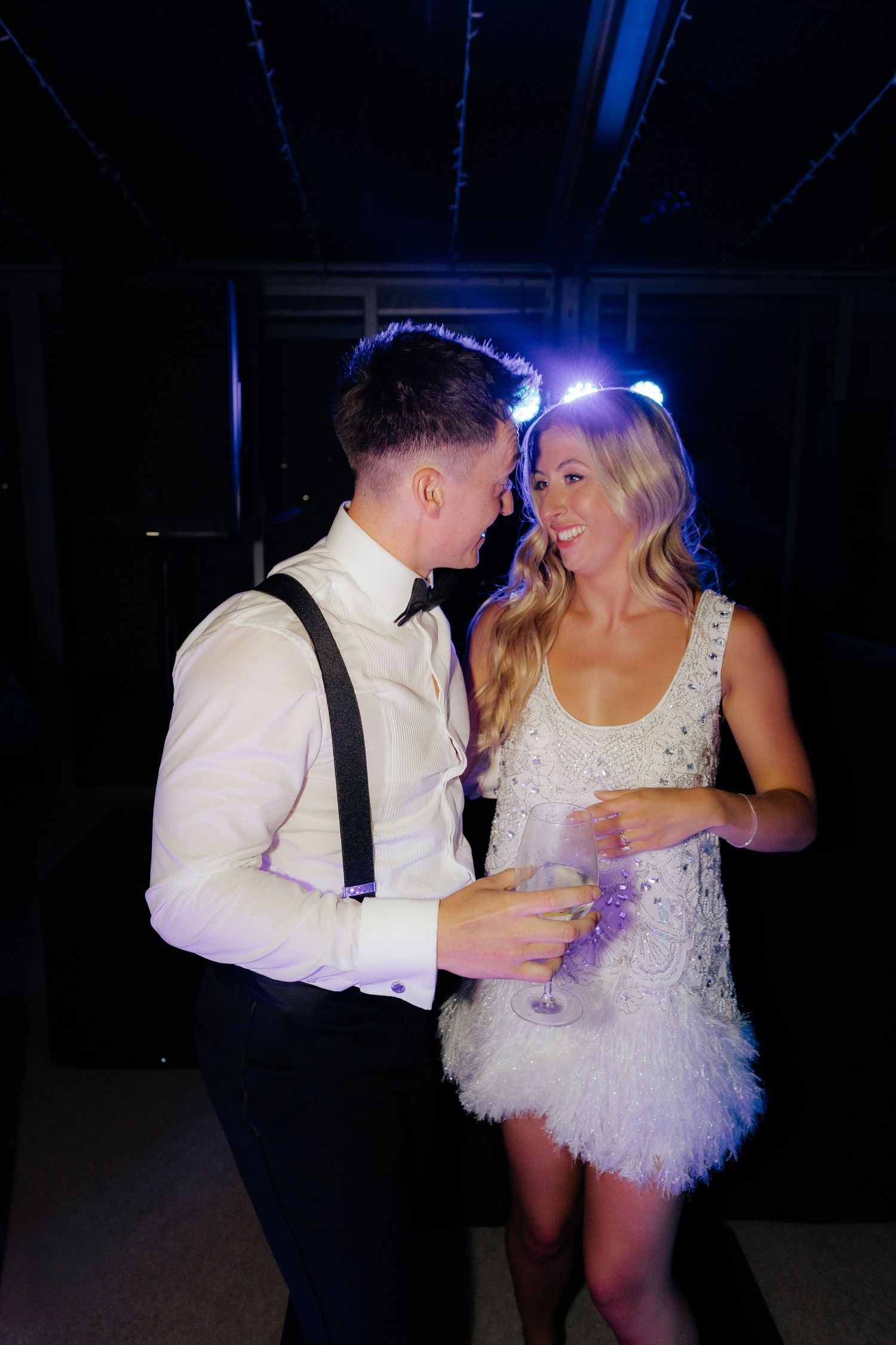 A couple in wedding attire share an intimate dance sequence in a dimly lit reception venue.