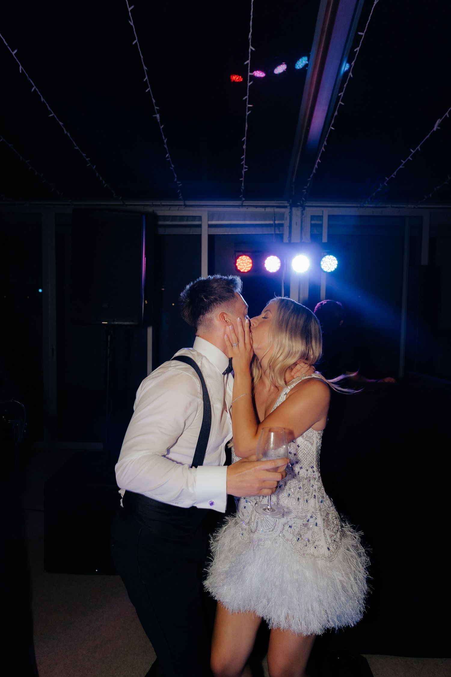 Couple sharing a romantic dance moment under blue stage lights at their wedding reception.