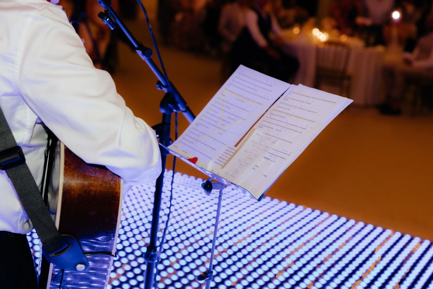 Musicians playing accordion instruments at a performance with sheet music on stands.