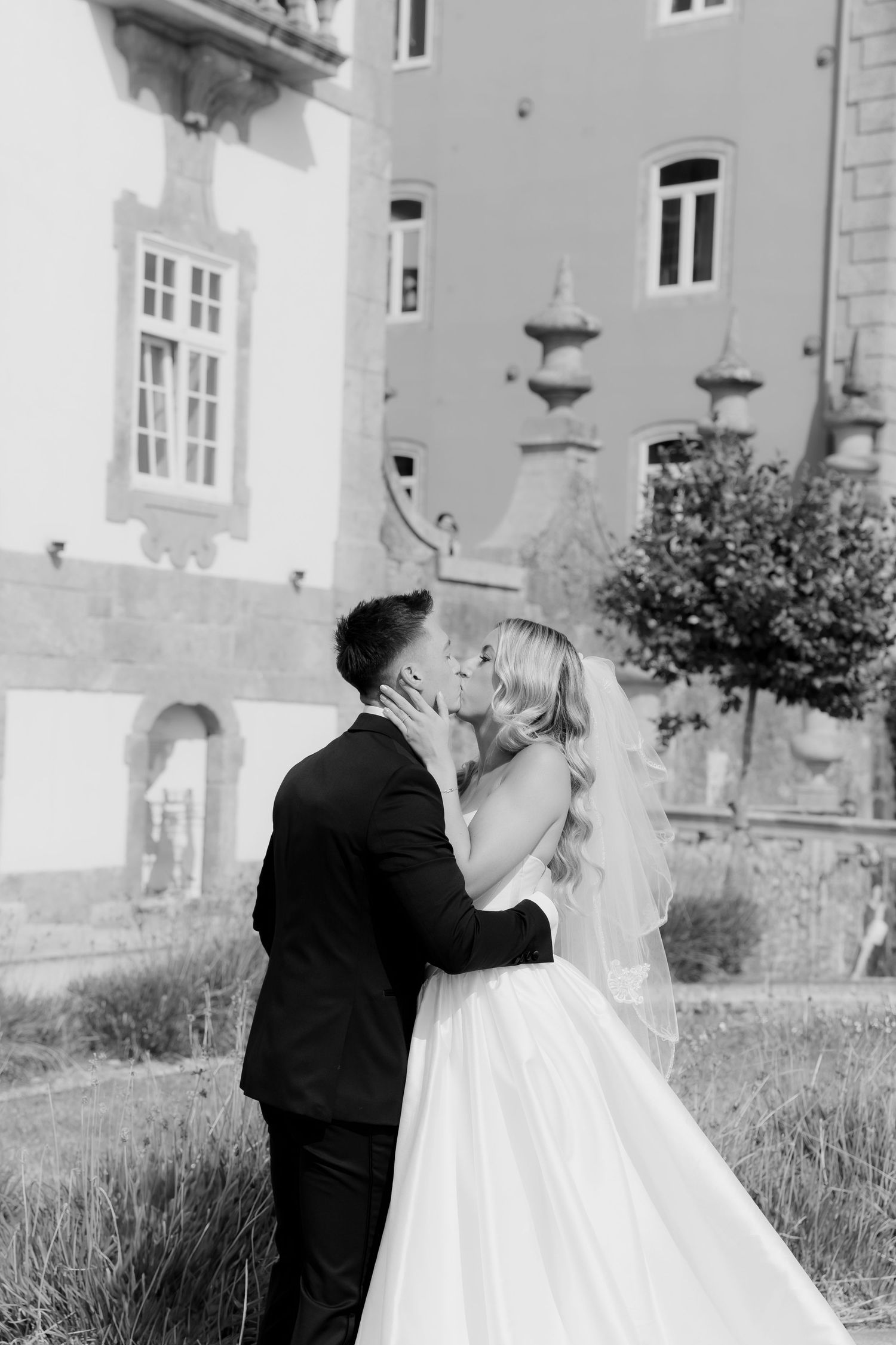 A romantic black and white wedding photo sequence showing a couple embracing near a historic stone building.