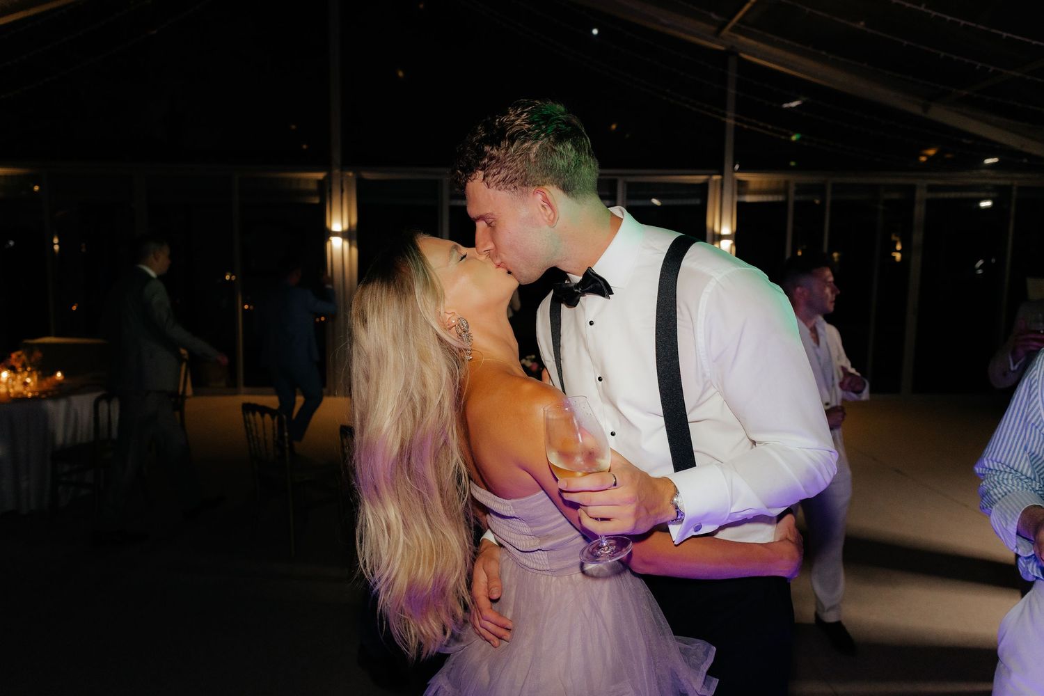 Couple dancing together in a dimly lit venue with romantic lighting and dark ambiance.