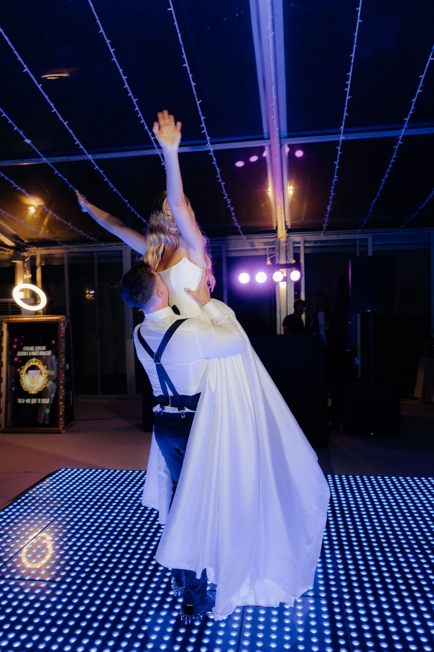 A couple dances together on an illuminated LED dance floor at a wedding reception.