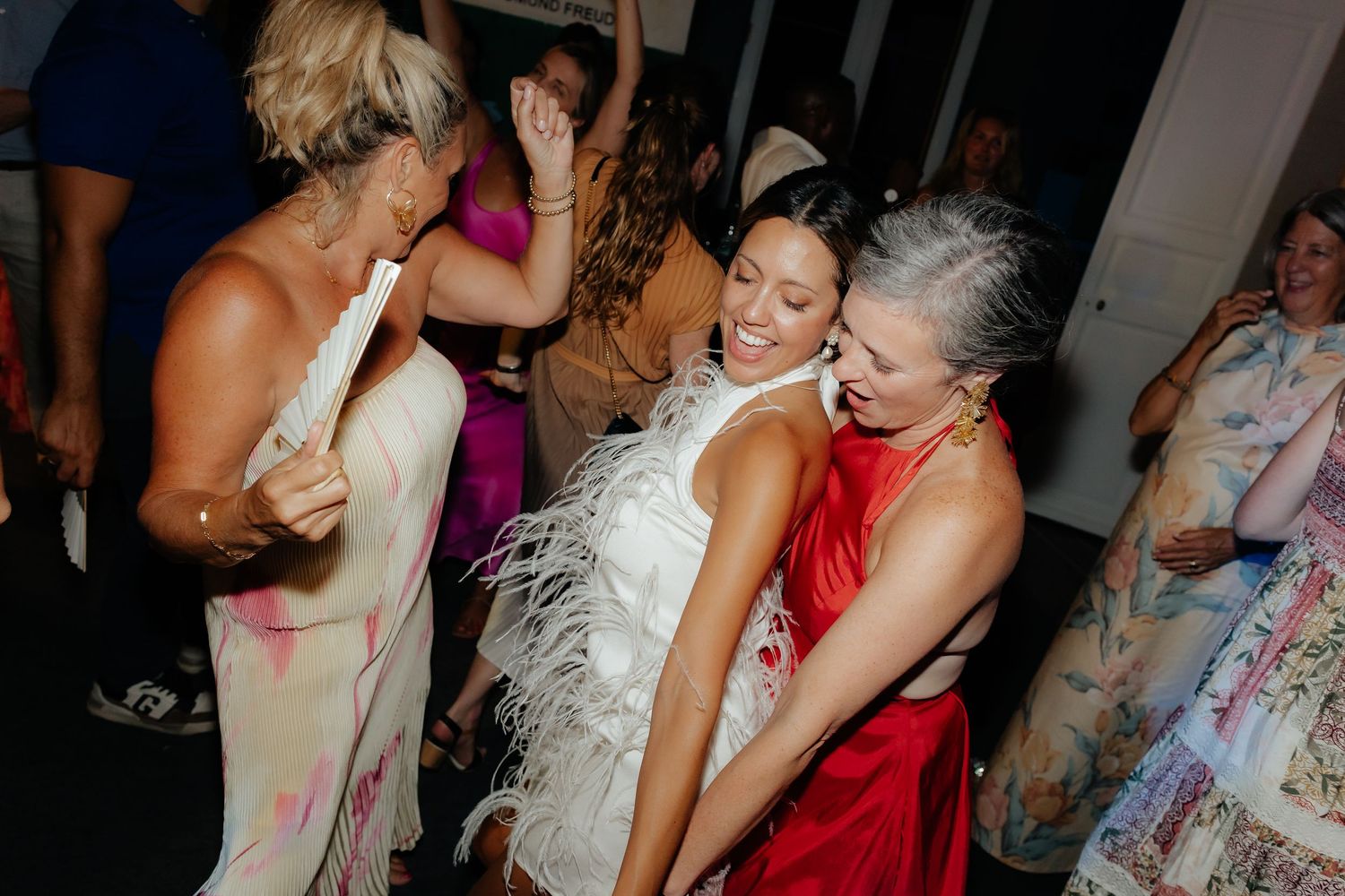 Lively dance floor scene at a wedding reception with people dancing in formal attire.