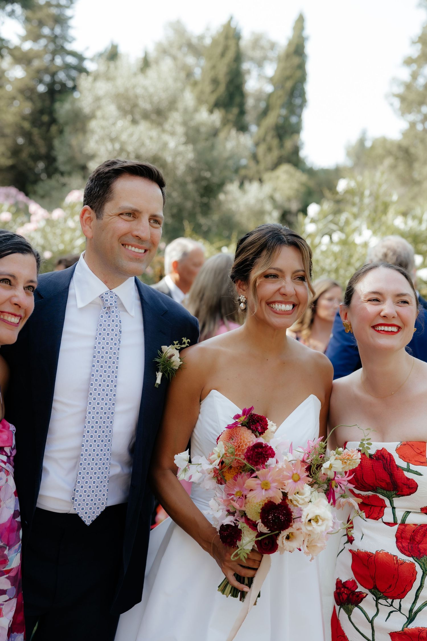 Wedding party members in navy and red attire smile together outdoors.