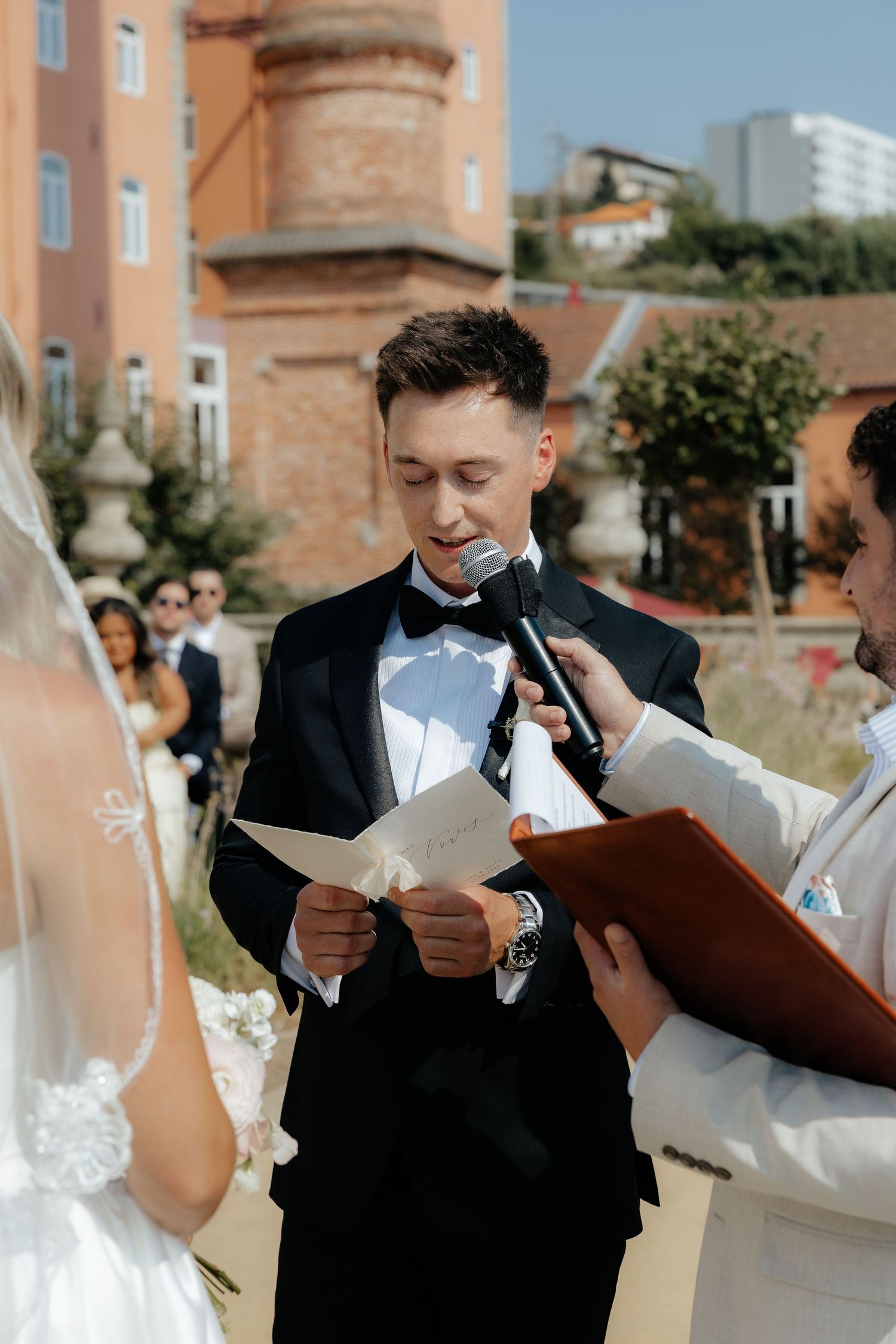 Wedding couple shares emotional first look reaction while reading letters to each other in outdoor venue setting.