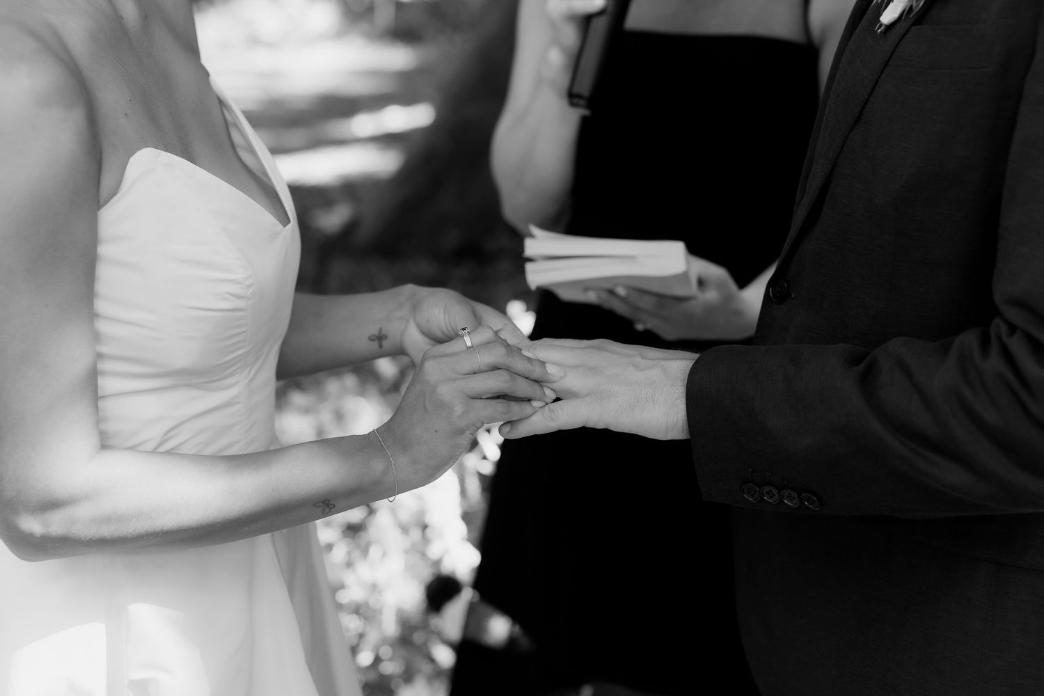 Intimate black and white photos of wedding ring exchange during ceremony.