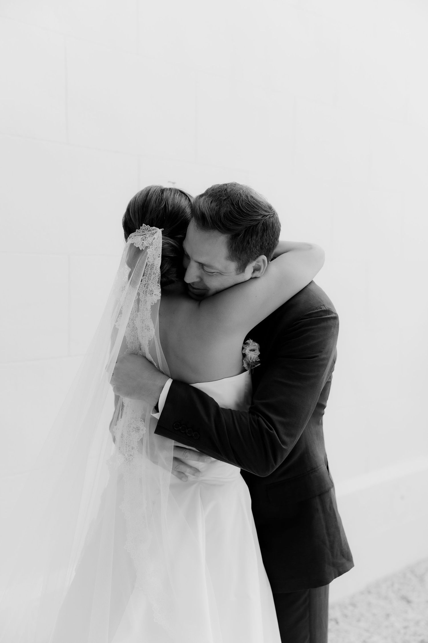 An intimate black and white wedding portrait capturing a tender embrace between newlyweds.