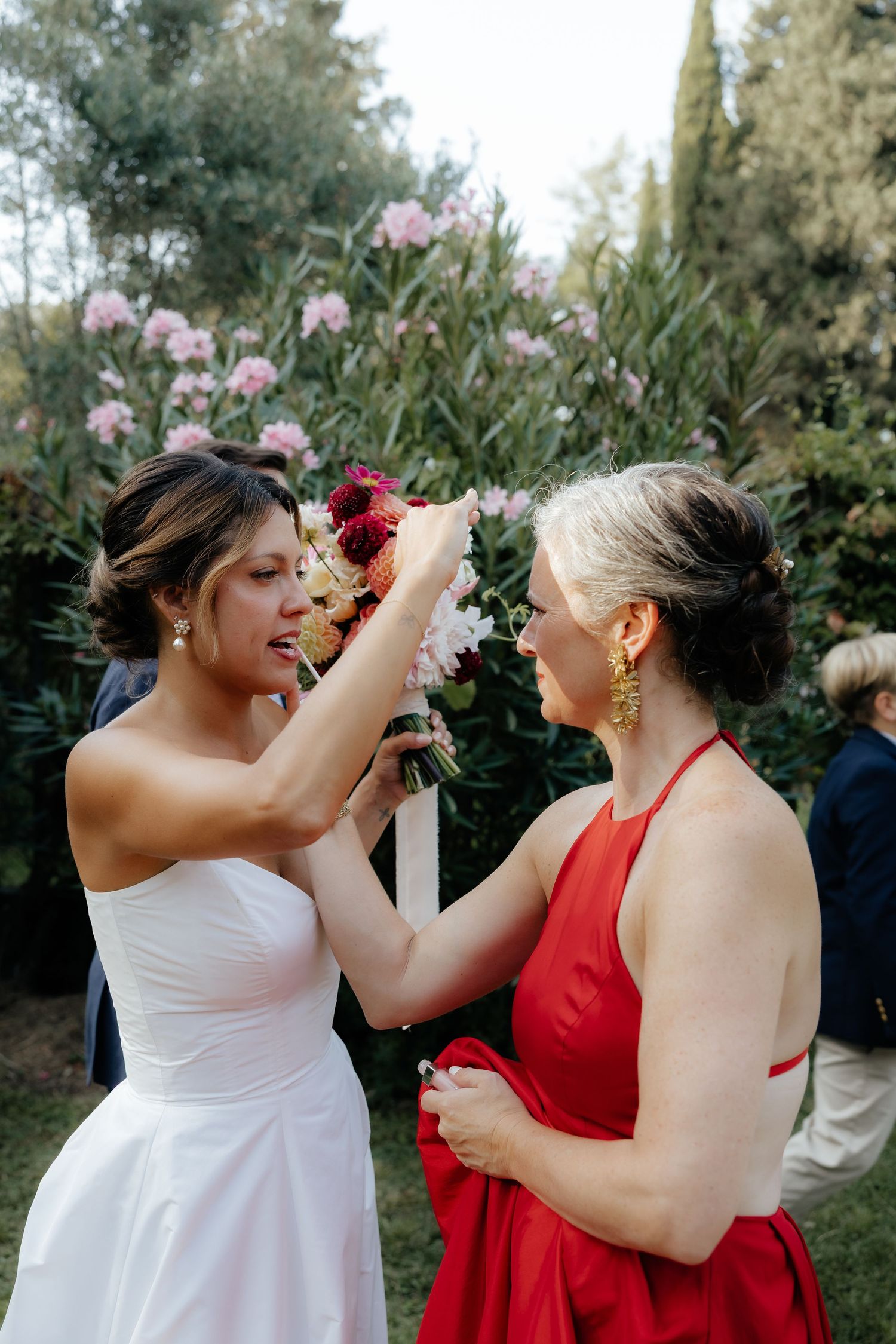 Wedding party members helping each other with final touches outdoors.