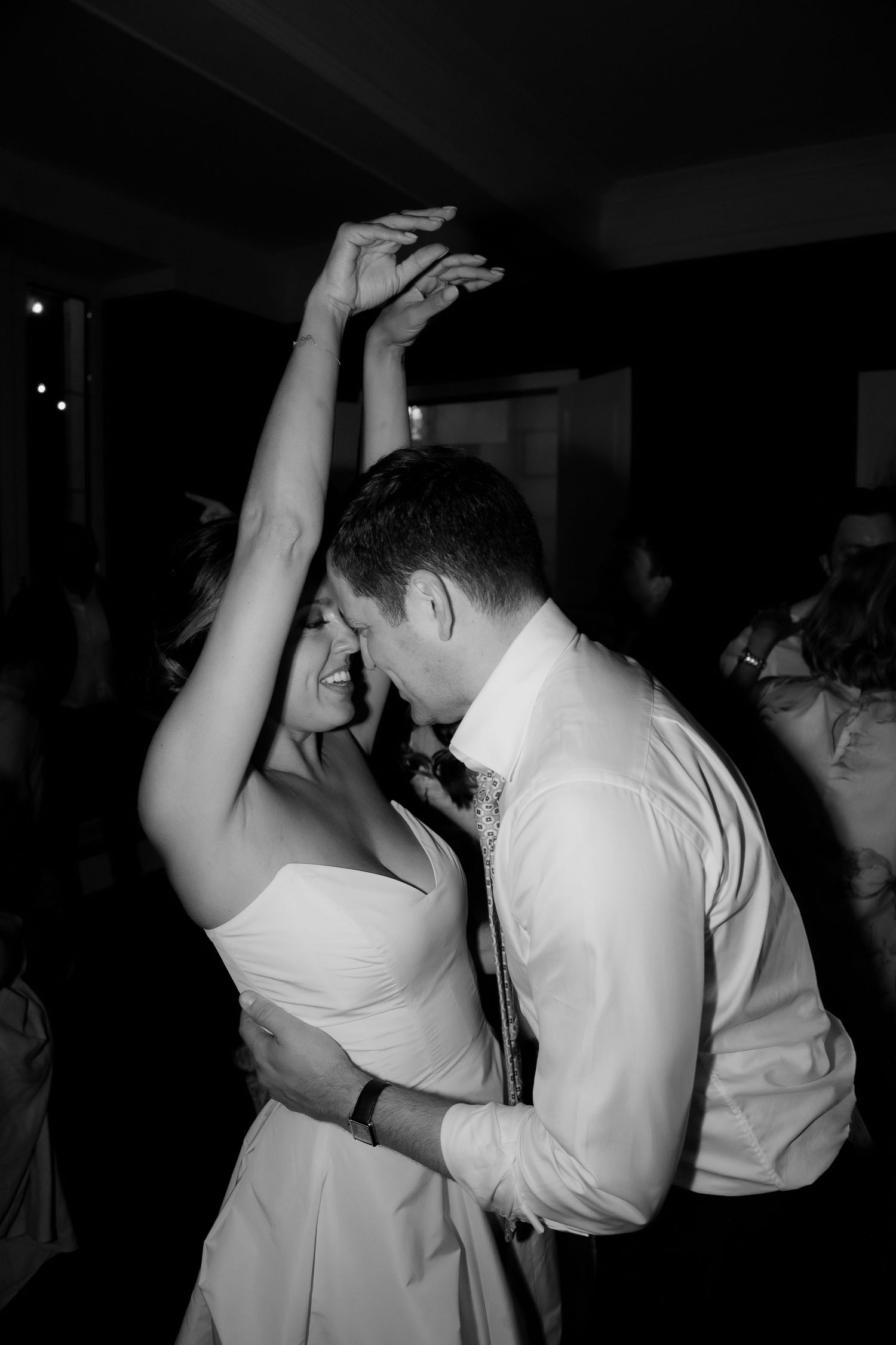 A couple dances closely in black and white at an evening reception.