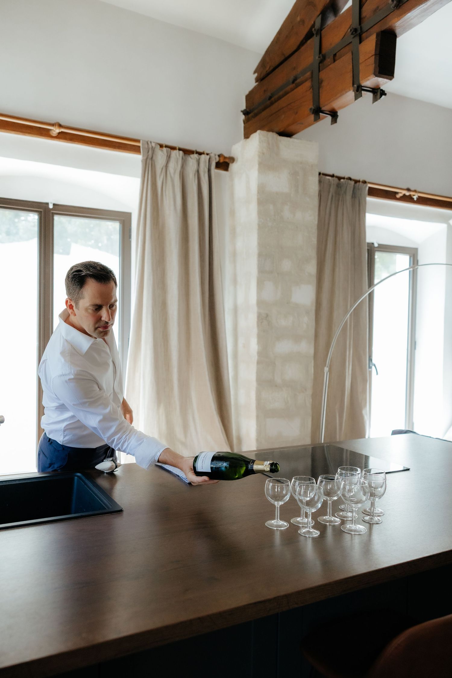 Wine glasses being arranged on a dark wooden table in an elegant indoor setting.