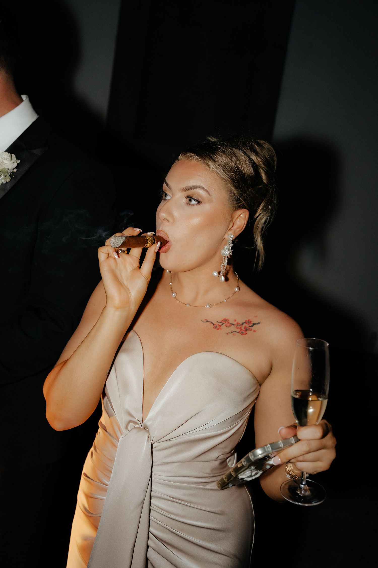 A person in a light colored dress takes a sip from a glass at what appears to be a party or celebration.