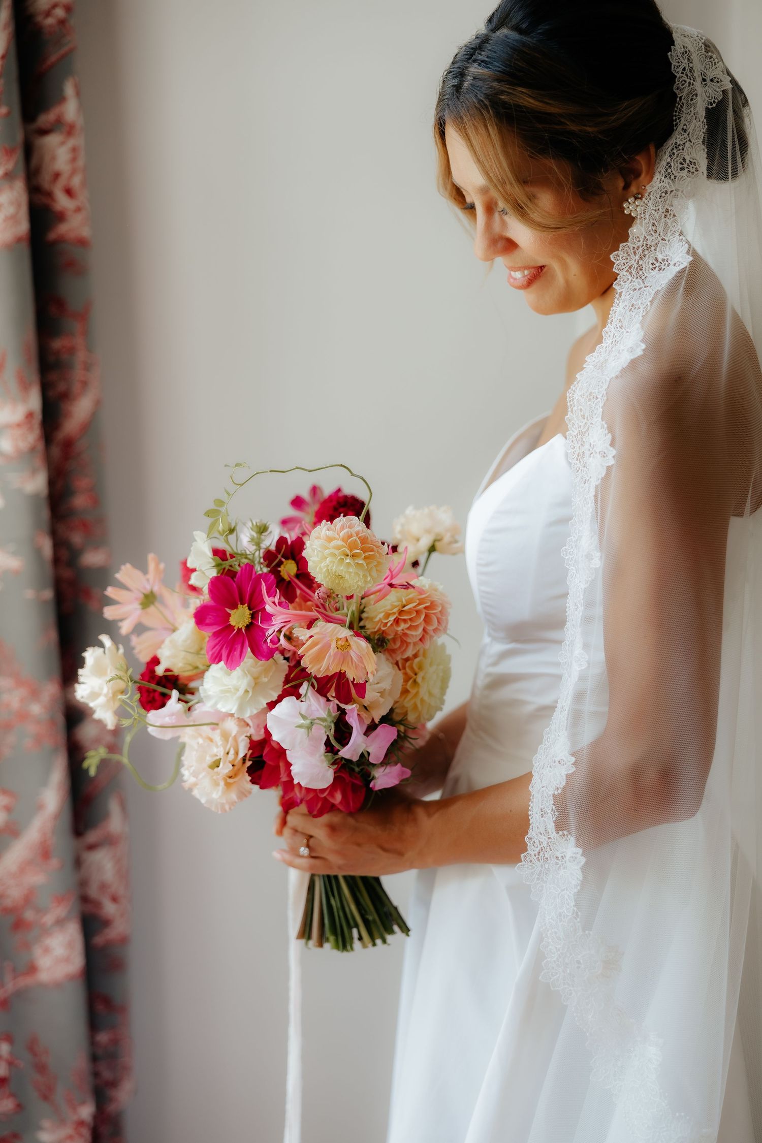 A bridal bouquet featuring vibrant pink and cream colored flowers against a light background.