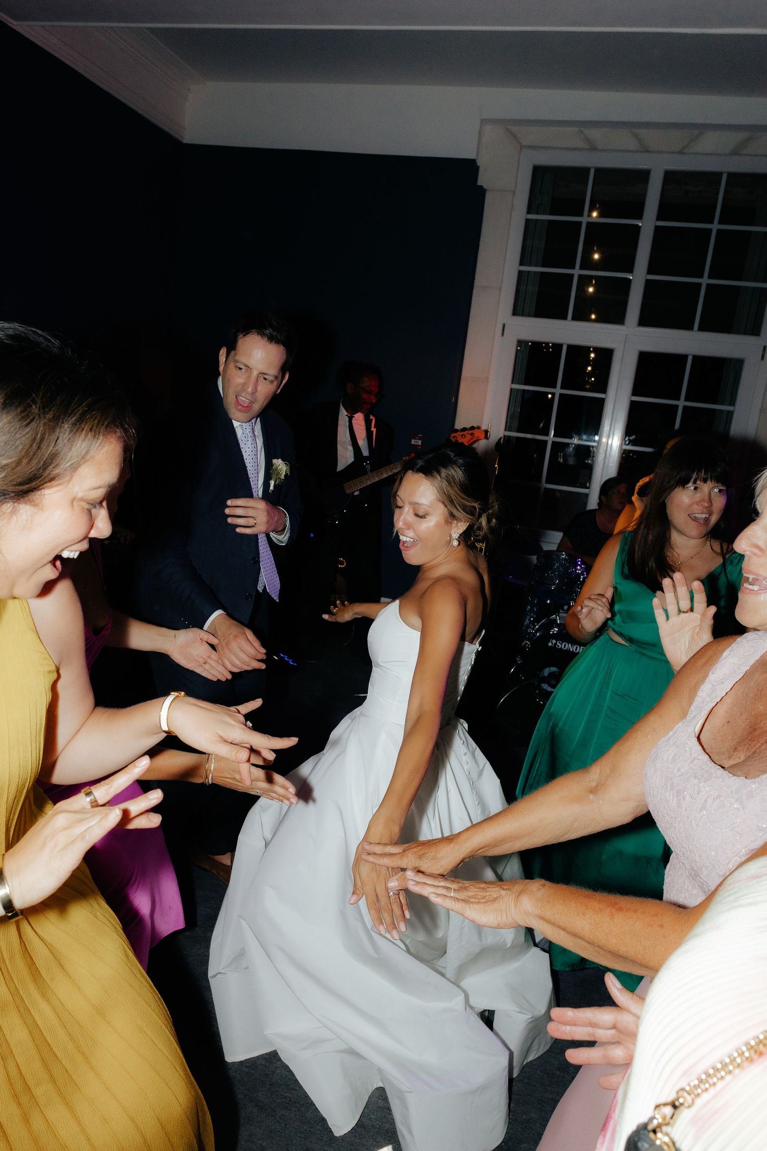 Party guests dance energetically at a nighttime celebration, creating a lively atmosphere with dynamic movements.