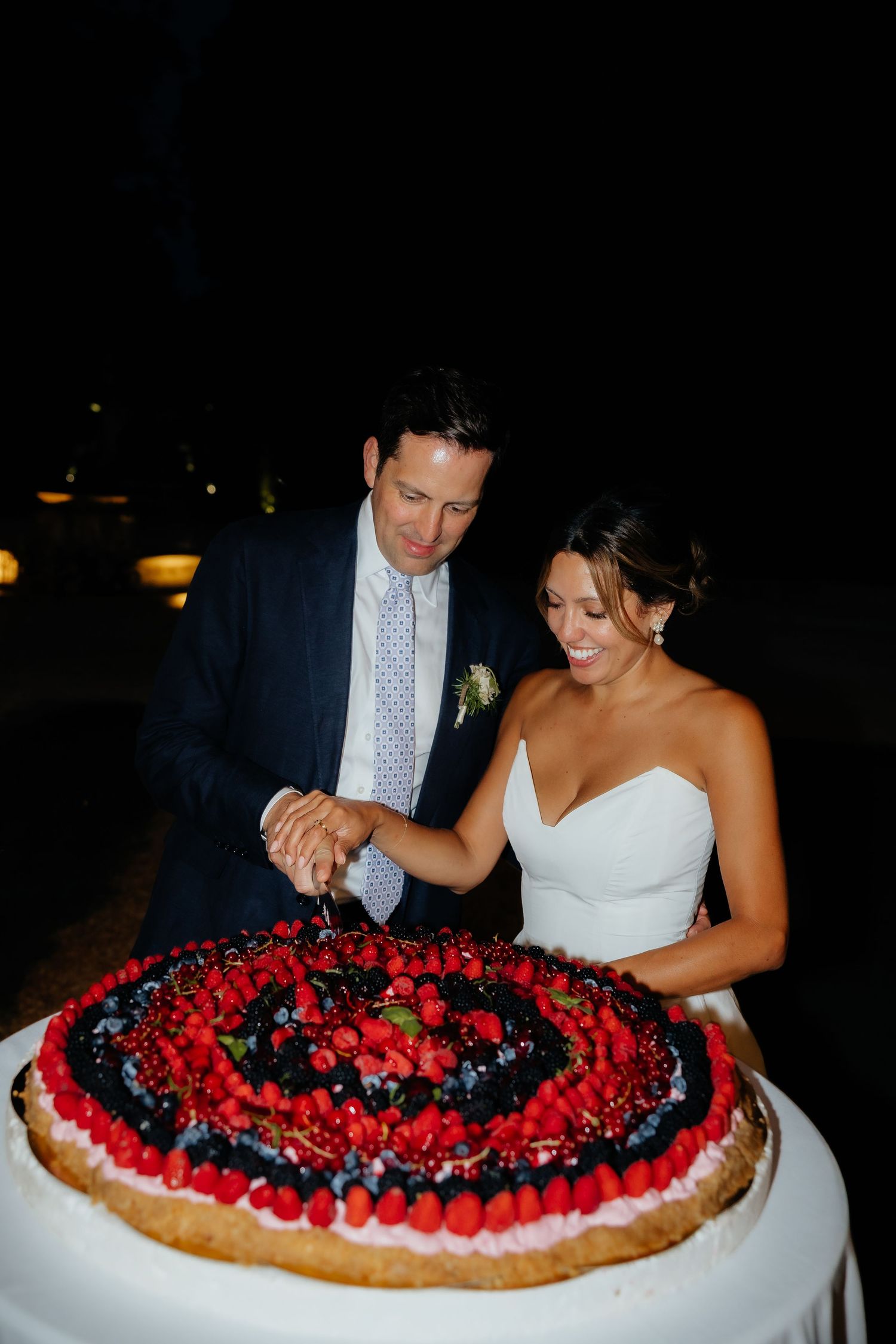 A couple enjoying a large berry tart decorated with red and dark berries in an elegant setting.