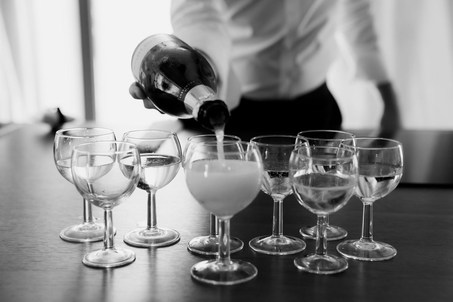 Empty wine glasses lined up in a row on a dark surface create an elegant black and white composition.