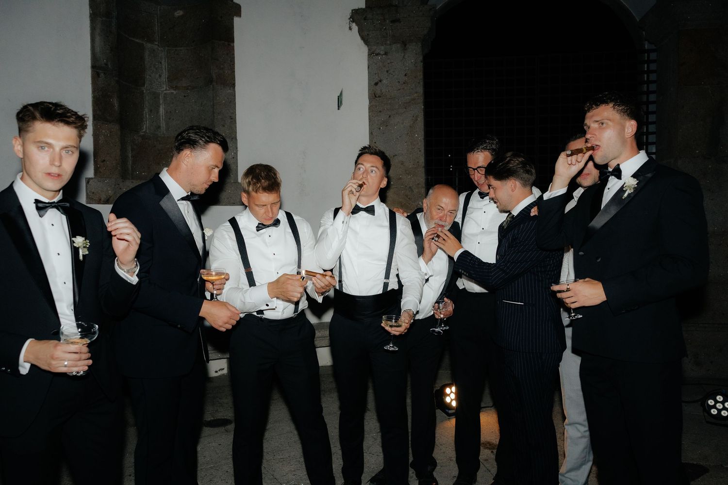 A group of people in formal black and white attire dance and socialize at an elegant event.