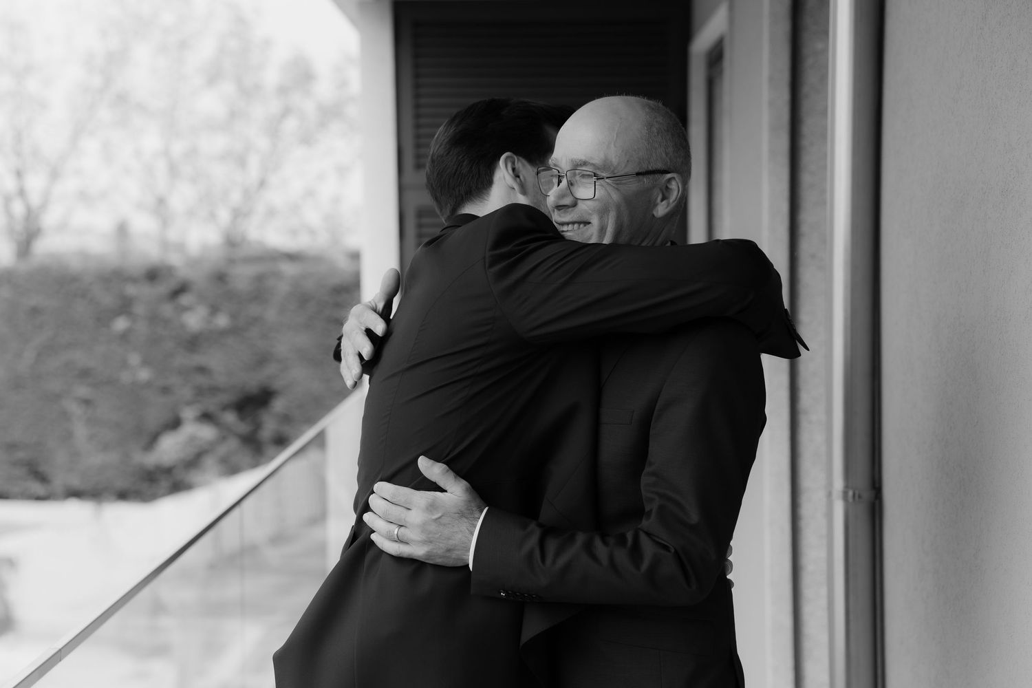 Black and white photo of two men sharing an emotional hug outdoors.