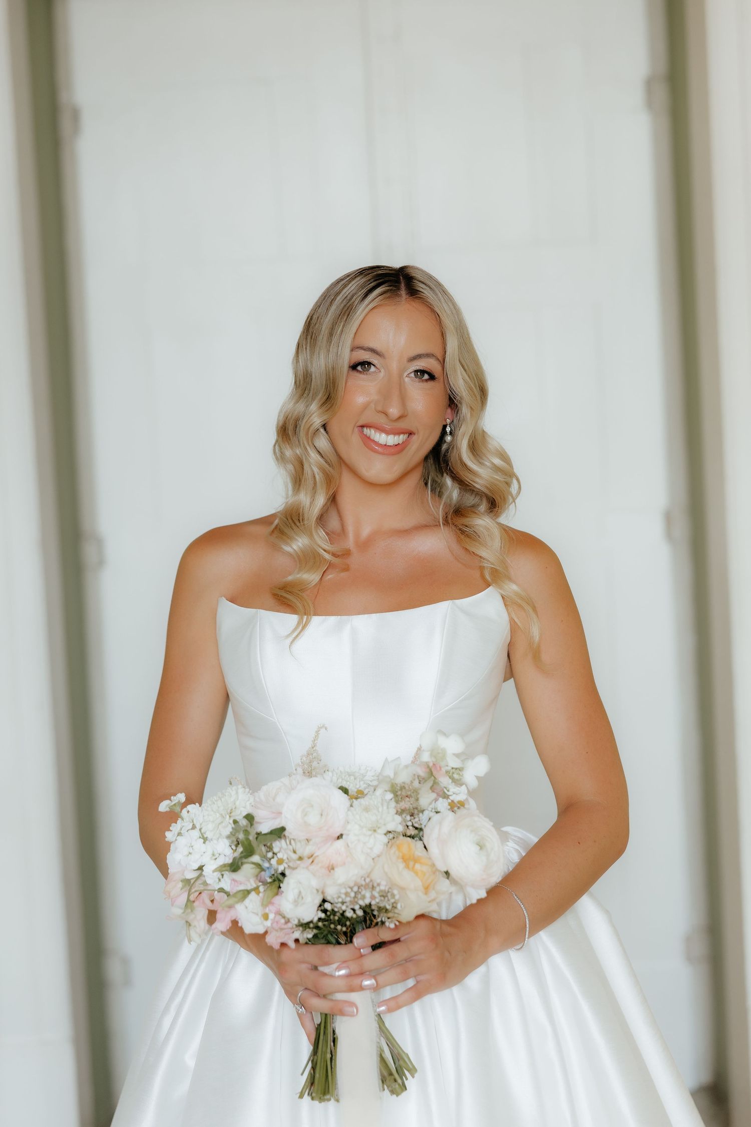 Four sequential photos show a bride in a white wedding dress holding a bouquet of white flowers in a light-filled room.