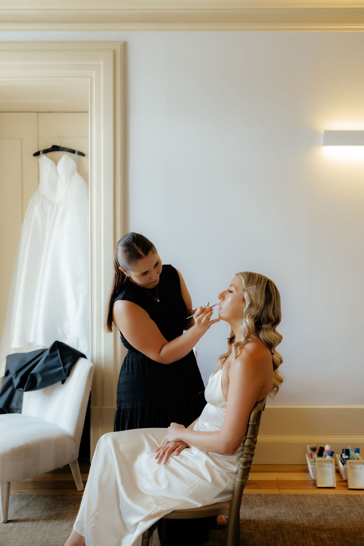 A sequence of photos showing a person getting their makeup professionally done in a bright, minimalist room.