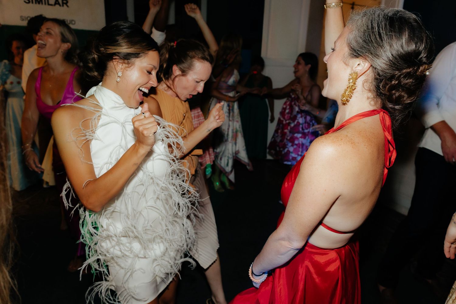 Couples dancing together at a lively wedding reception party with festive decorations in the background.