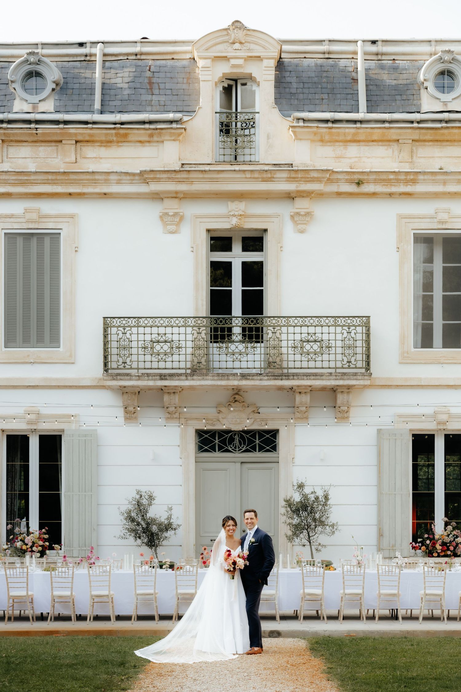 A grand white mansion serves as backdrop for an elegant outdoor wedding reception setup.