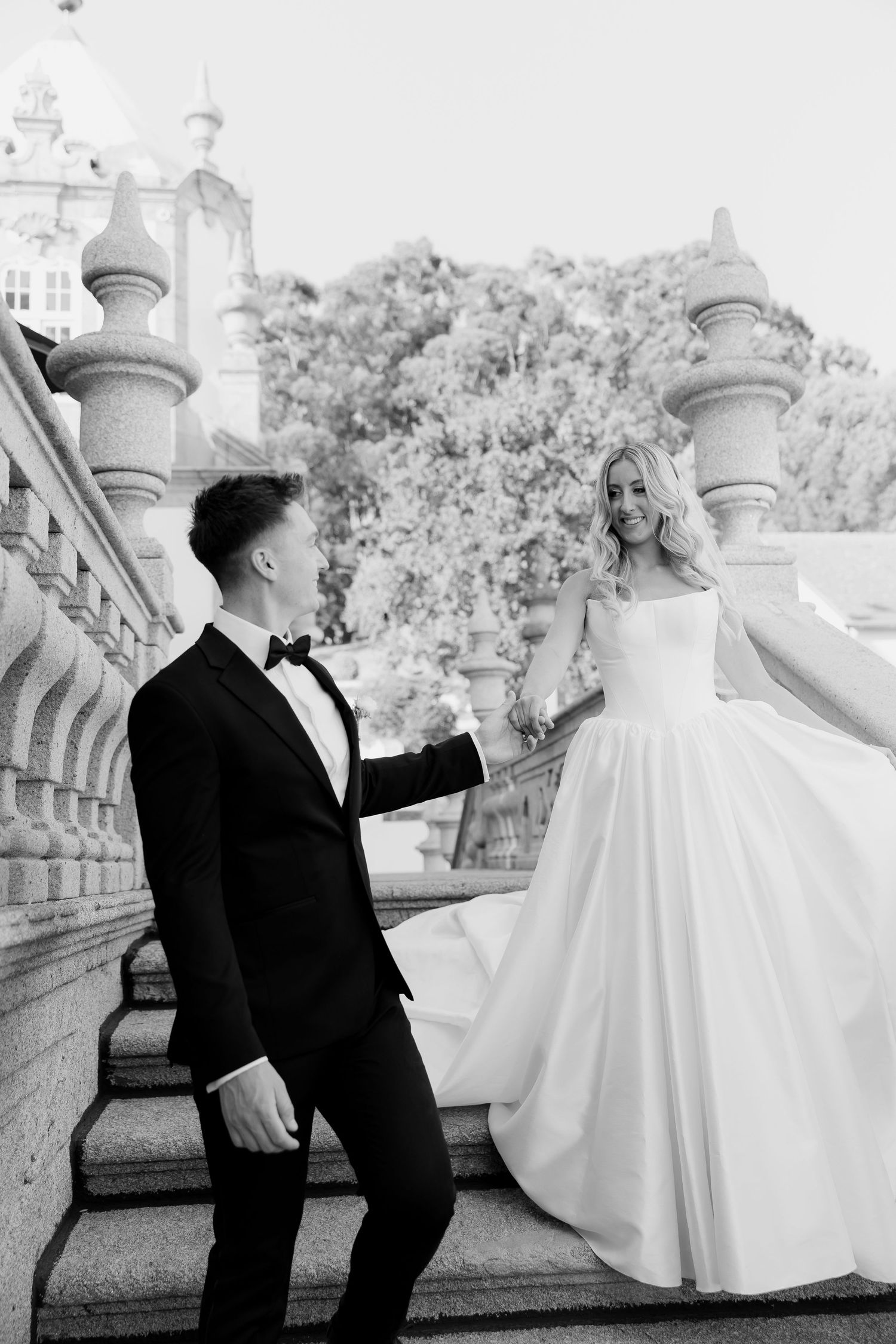 A black and white wedding photo sequence shows a couple playfully interacting on a balcony with ornate stone railings.
