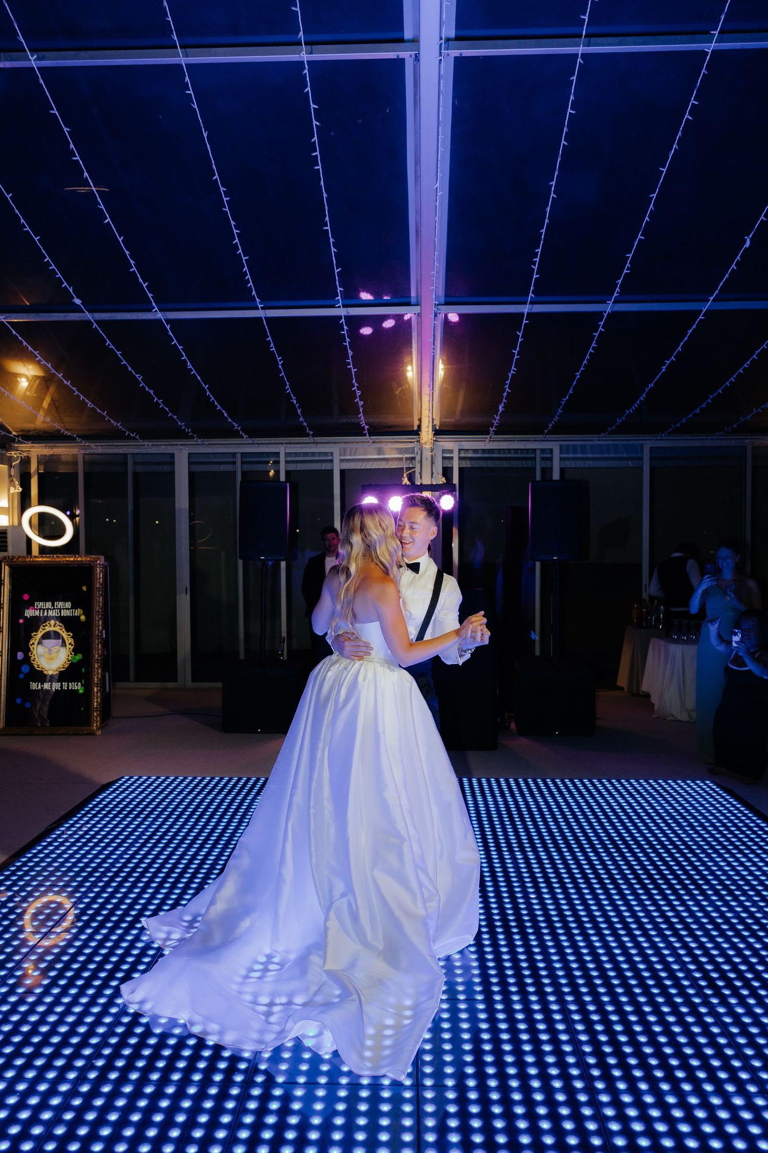 A bride in a white wedding gown walks across an illuminated LED dance floor creating a stunning visual effect.