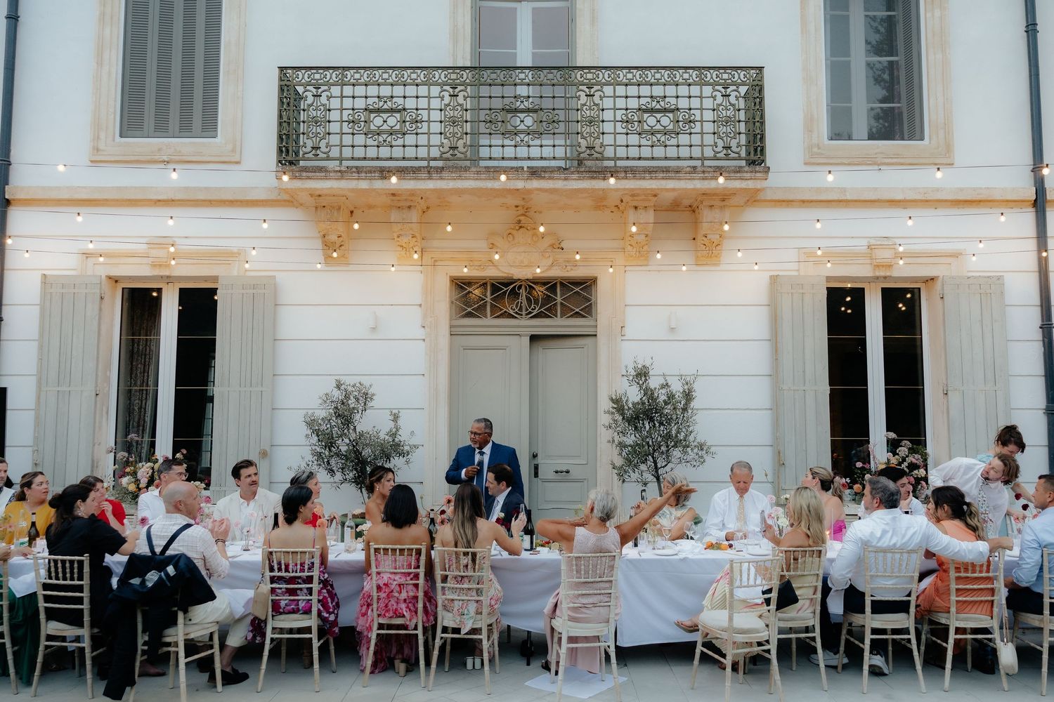 Panoramic view of an elegant outdoor wedding reception with white tables and chairs set against a classic building facade.