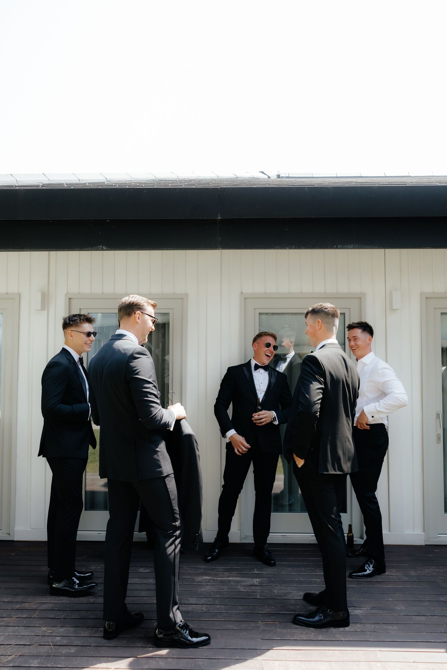 A sequence of photos showing groomsmen in black suits helping each other prepare before a wedding ceremony.