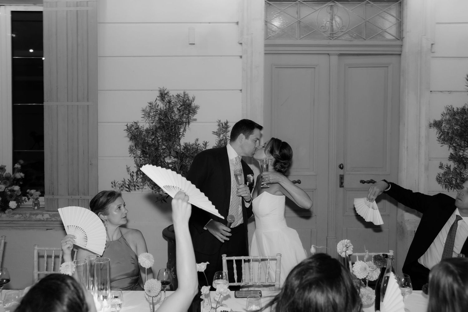 Wedding party dances and celebrates with raised napkins during an indoor reception celebration.