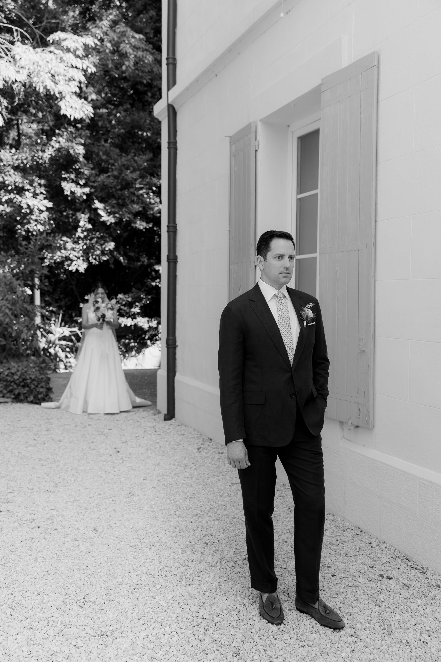 Black and white wedding photos showing a couple's first look outside a white building.