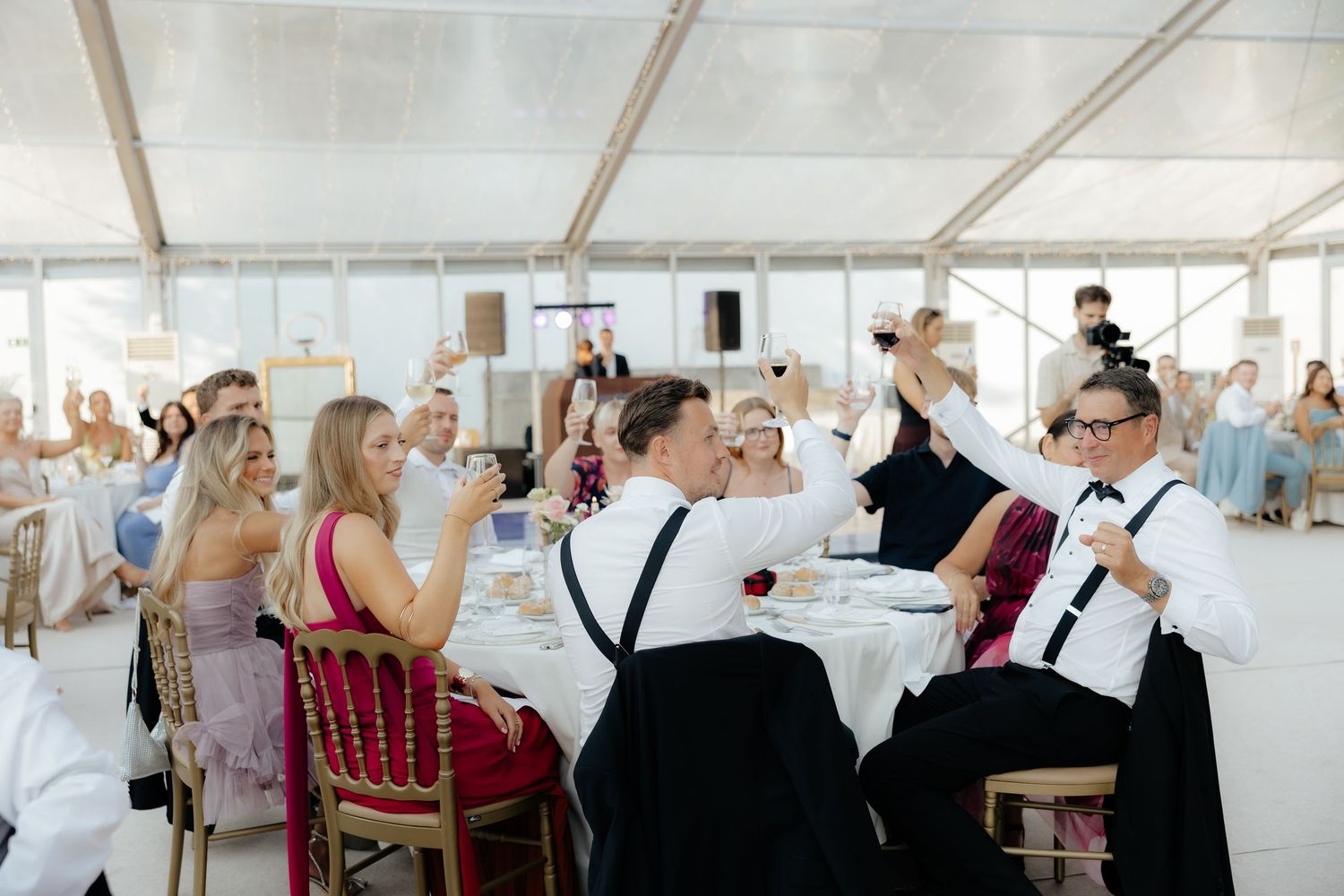 People seated at long tables in a bright cafeteria or dining hall during a social gathering.
